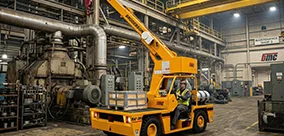 Broderson IC-35 carry deck crane handling indoor maintenance lifts in a busy plant.