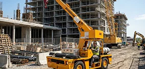 Broderson IC-35 carry deck crane moving materials on a busy construction site.