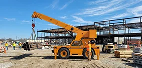 Broderson IC-400 Carry Deck Cranes handling pipe lifts with steady control on a busy site.