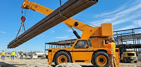 IC-400 Carry Deck Cranes lifting bundled pipes on a busy site, with controlled positioning.