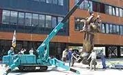 Maeda MC305C mini spider crane lifting a large sculpture on an outdoor construction site