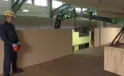Maeda MK3053 crane lifting a large panel indoors with operator supervision