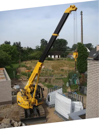 Mini crawler crane lifting materials at a residential construction site