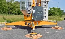 Potain EVY 30-23-4 T set on outriggers with timber mats, positioned for a stable, level setup.