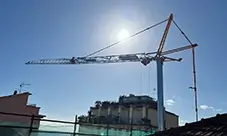 Potain EVY 30-23-4 T tower crane operating over an urban jobsite, providing extended reach for daily lifts.