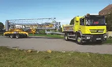 Potain Hup M 28-22 A in transport mode, towed behind a truck with the jib folded.