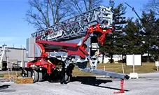 Potain self-erecting tower crane staged and ready for setup, with the jib folded for transport and the unit positioned on site.