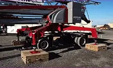 Potain Igo MA 21 self-erecting tower crane set on outriggers with timber mats, staged on site before erection and lifting operations.